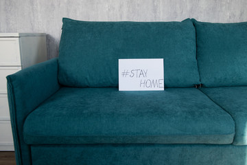 Empty sofa with stay home hashtag on white paper