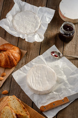 Camembert cheese, jam and croissant on a rustic wooden table