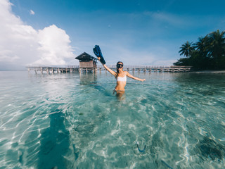 Young blonde in goggles standing on shallow and showing flippers