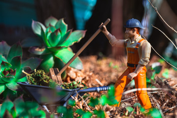 Worker is cleaning weed with wheelbarrow, shovel and broom.