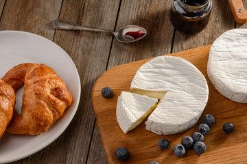 Croissants, blueberries, jam and Camembert cheese on wooden table