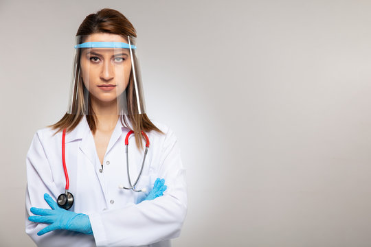 Woman of doctor with face mask looking at camera on gray background, corona virus concept.