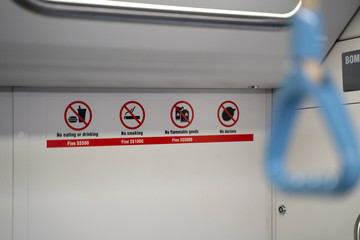 Warning sign on Train on Singapores MRT.  Fine for eating durian fruit. blurred handle in foreground.