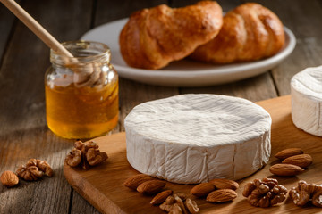 Almonds, walnuts, honey and Brie cheese on a wooden table
