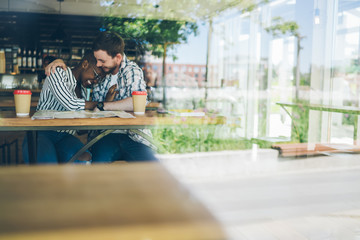 Happy diverse couple laughing in cafe