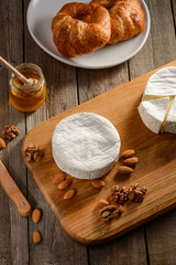 Brie cheese, almonds, walnuts and honey on a wooden table