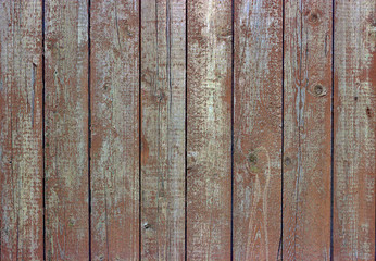 Weathered wooden plank fence texture with brown paint residues

