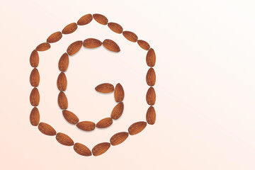 Letter G of the English alphabet from nuts in hexagon shape. Food pattern made from nuts alphabet for shop and diet