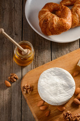 Fototapeta premium Top view on Camembert cheese, nuts, honey and croissants on a wooden table