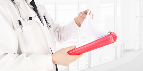 Closeup of a doctor reading a patients medical chart in a modern medical facility. The man is unrecognizable.