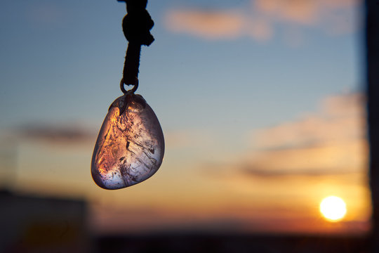 Amethyst pendant in a light of a setting sun of a city outskirts.            