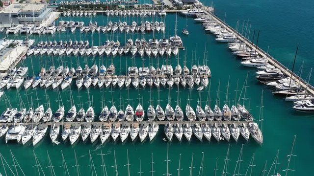 Croatia, marina Kastela, 15 September 2019: Drone view point on moored in an equal row sailboats, participant of a sailing regatta, piers, a lot of boats, mountains is on background