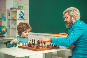 Father with son playing Chess at home. Happy two generations of men have fun and playing Chess. Cute little boy playing chess with Parents.