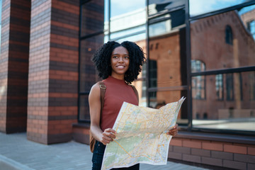 Black joyful lady using map traveling in town