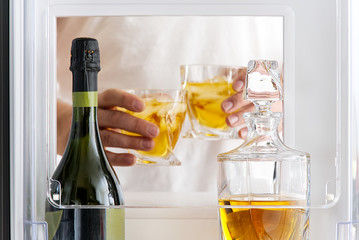 open hatch of a mini bar in a modern refrigerator. home mini bar in the fridge. a man took two...