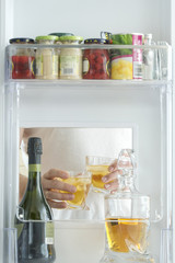 open hatch of a mini bar in a modern refrigerator. home mini bar in the fridge. a man took two glasses with alcohol from the counter, view from the refrigerator.