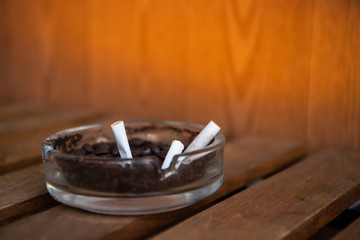 Cigarette in glass ashtray.