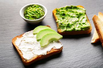 Tasty avocado sandwiches on dark background