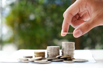 Male hand putting money coin on passbook, Saving money concept.
