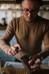 Bartender preparing cocktail based on gin, birch juice and spraying essential oil of frankincense into pitcher.