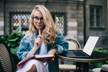 Fototapeta premium Thoughtful student with notebook and laptop
