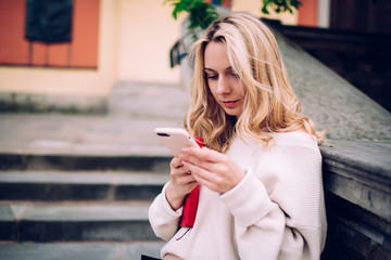 Woman using smartphone while leaning on stone railing