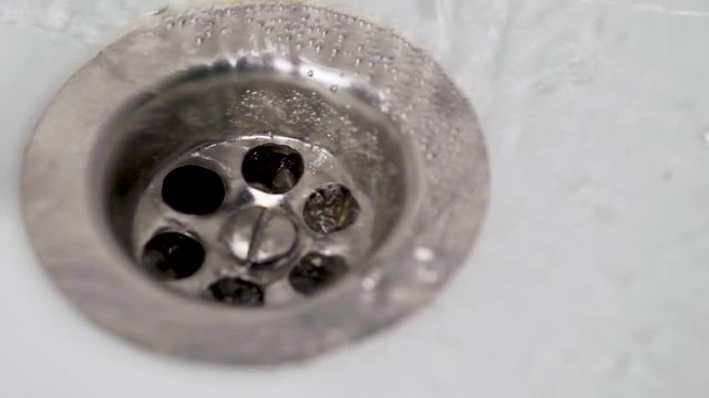 slow-motion water flows into the drain hole 120 fps to 25 fps