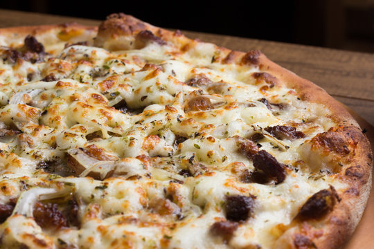 Delicious meat pizza on wooden board. Made with Mozzarella, picanha meat, onion, cheese, tomato sauce. Filet Steak, meat. Horizontal photograph with blurred background.