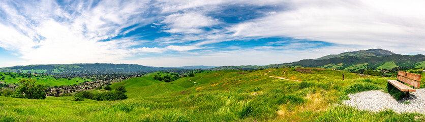 Fototapeta na wymiar Panoramic view with a park bench overlooking Camino Tassajara on the slope of a hill in Sycamore Valley Preserve Contra Costa County Danville, California.