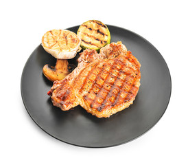 Plate with cooked pork steak and vegetables on white background
