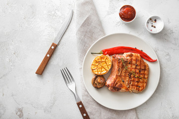 Plate with cooked pork steak and vegetables on white background