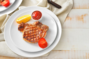 Plate with cooked pork steak and sauce on table
