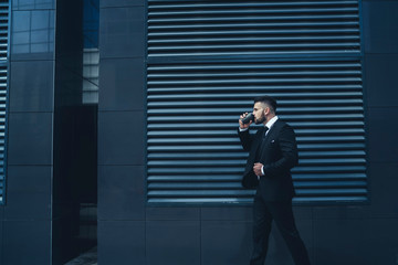 Fototapeta premium Boss sipping hot drink outside modern building