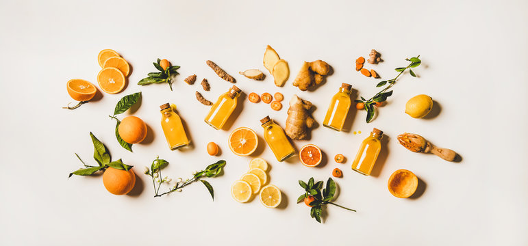 Immune boosting natural vitamin health defending drink to resist virus. Flat-lay of fresh turmeric, ginger and citrus juice shots over white background, top view. Vegan Immunity system booster