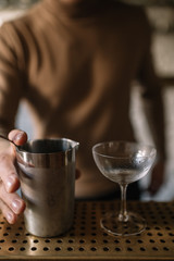 Bartender pouring a cocktail from a mixing pitcher into a cooled glass. Smooth image with shallow depth of field.