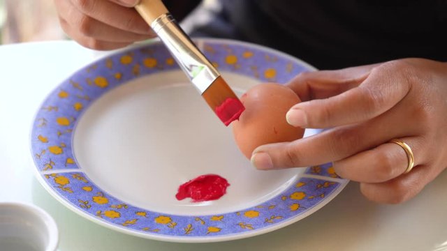 A teenager paints an Easter egg red with a brush, in view of the approaching Easter. video shot in 4k