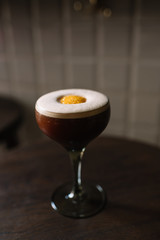 Espresso martini cocktail decorated with slice of orange zest. Smooth image with shallow depth of field.