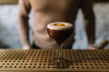 Espresso martini cocktail decorated with slice of orange zest. Smooth image with shallow depth of field.