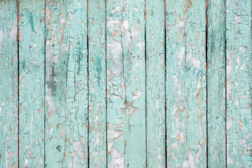 Fototapeta na wymiar Background from wooden boards with peeling paint top view. Green old cracked paint on a wooden surface. Wooden planks covered with old faded oil paint.