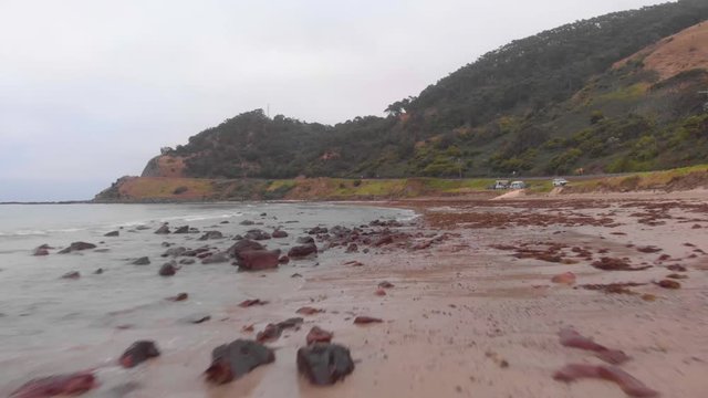 low flying aerial drone over rocky wet beach on misty morining