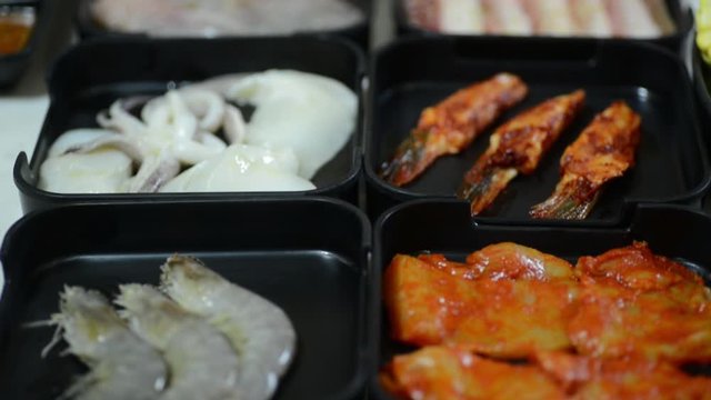 Flavored Meats And Seafood Along With A Bunch Of Sauces On Black Containers. -wide shot