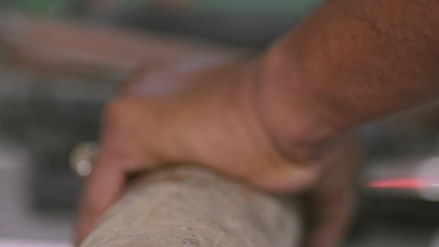 Closeup View Of The Tip Of A Brass Round Bar With Hole Held Tightly By A Craft Worker While Cutting It With A Hacksaw - Closeup Shot
