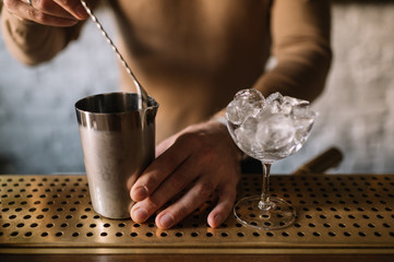 Bartender preparing cocktail based on gin, birch juice and spraying essential oil of frankincense...