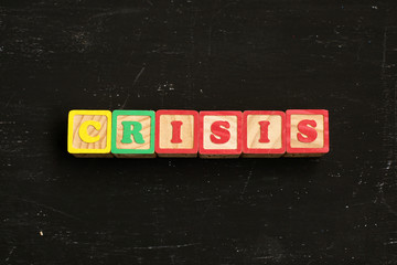 Word CRISIS made from wooden letters lies on a black table