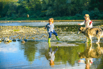 Obraz na płótnie Canvas Stony river. Little boy and girl playing in the river. children throw stones. Kids play in water at mountain river. Outdoor fun. Active recreation with children.