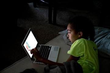Girl creating art on touch screen laptop computer at night in the dark 