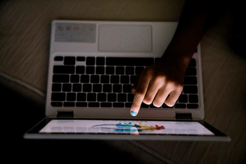 Girl creating art on touch screen laptop computer at night in the dark 