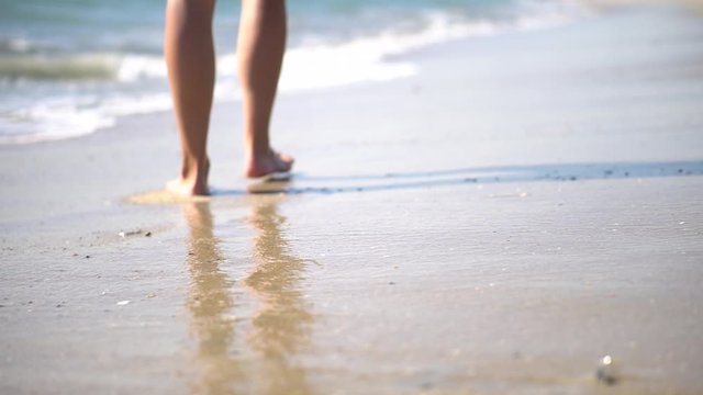 Young sexy woman's feet walking on the beach ocean - close up