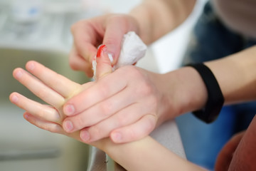 Obraz na płótnie Canvas Mother hands applying antibacterial medical adhesive plaster on child's finger after wounding at home. First aid for kids after injury