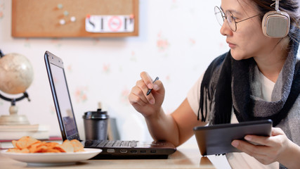 Caucasian Asian woman works from home during the Coronavirus crisis. Social Distancing and New...